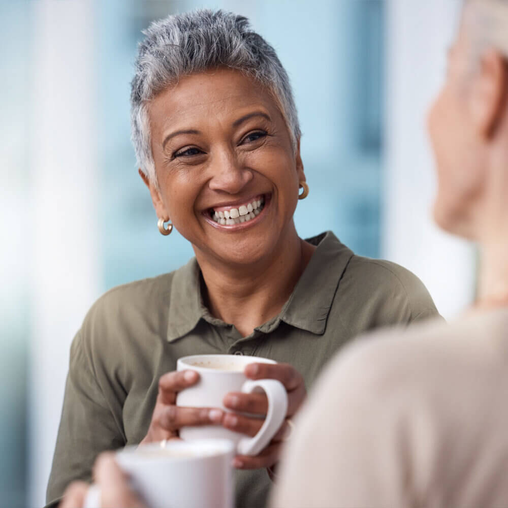 lady smiling enjoying a cup of tea with care professional