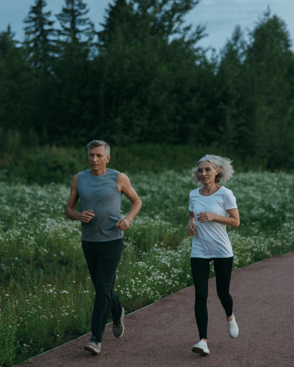 Older man and woman jogging outdoors in the countryside at dusk