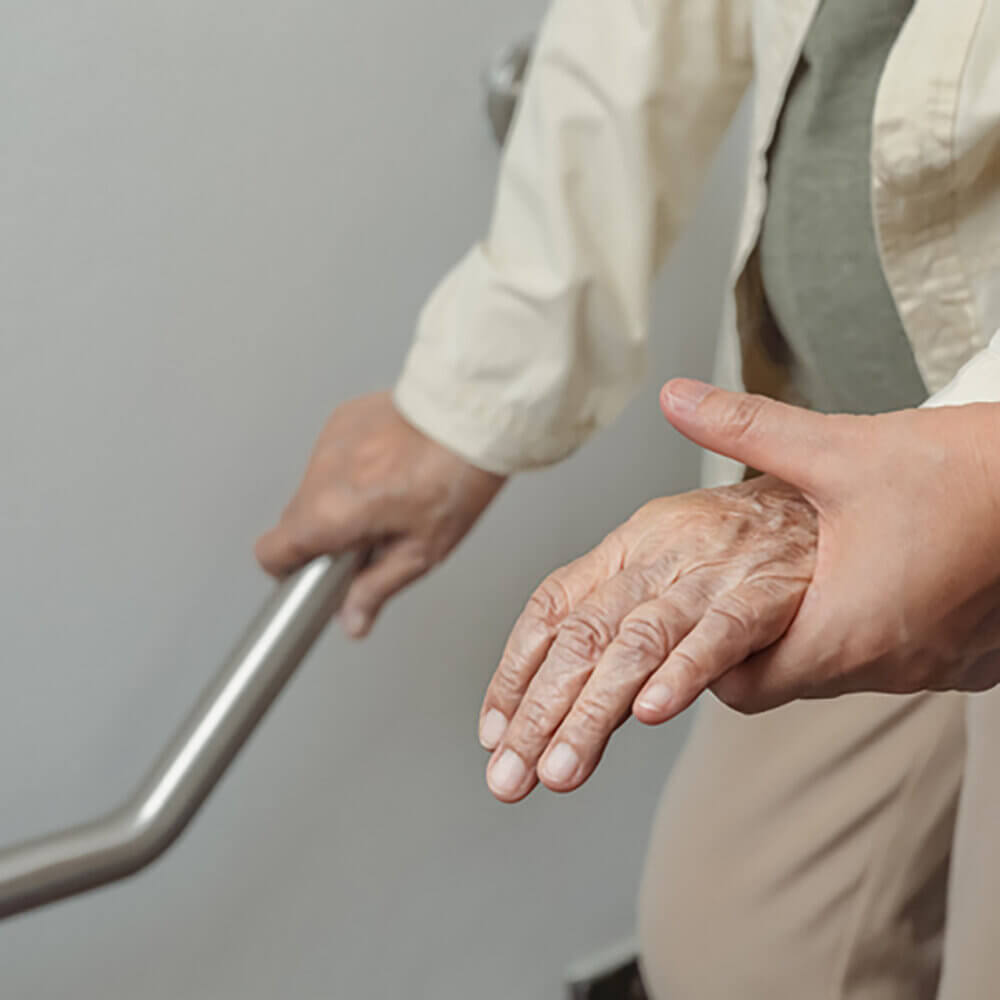 Elderly person holding onto a handrail for support.